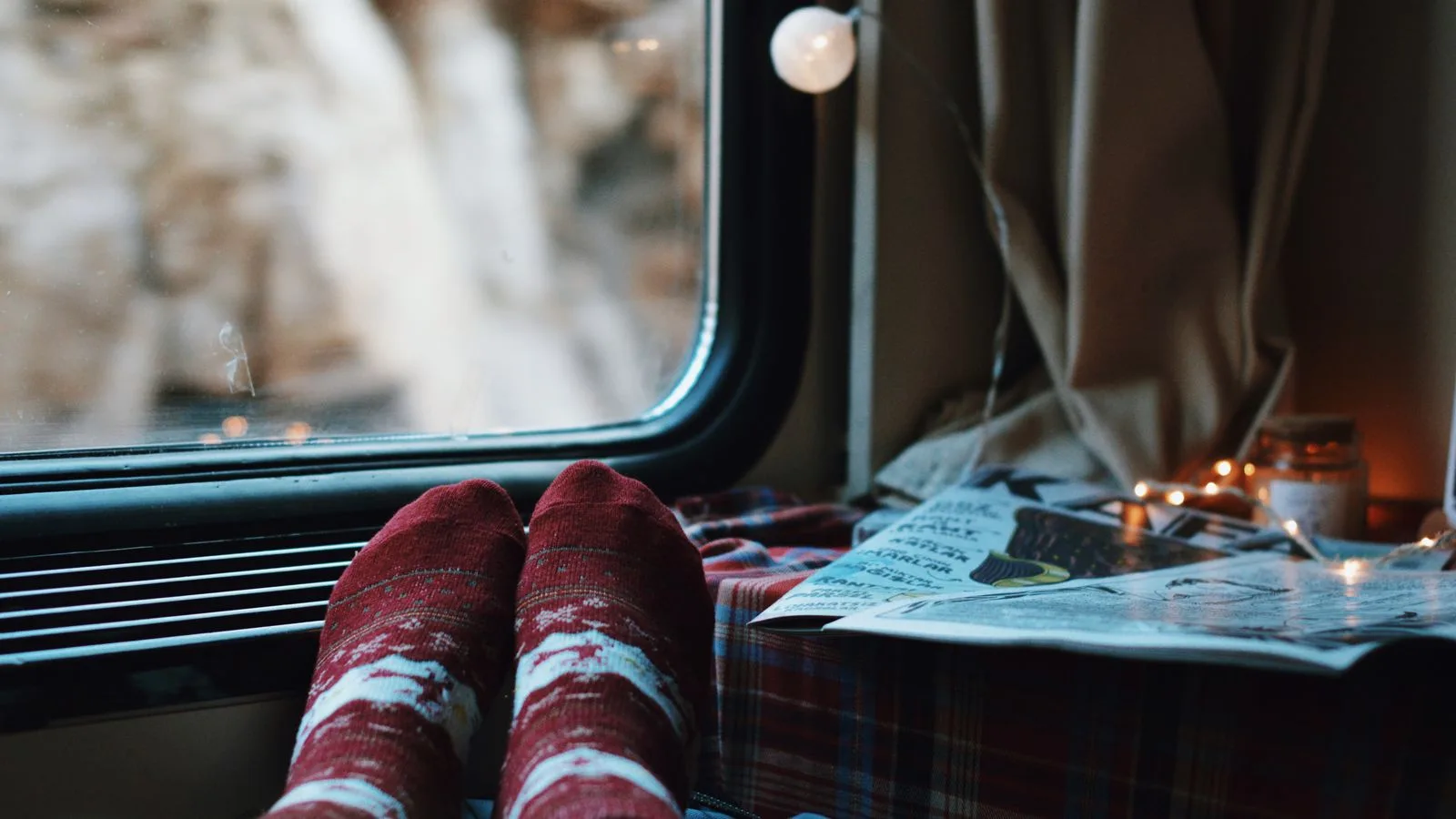 Relax by the window with festive socks and warm decor during winter train journey.