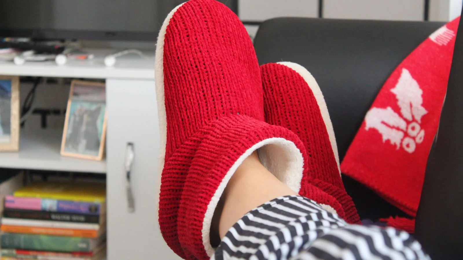 Comfortable relaxation at home with fluffy red slippers and a cozy setting.
