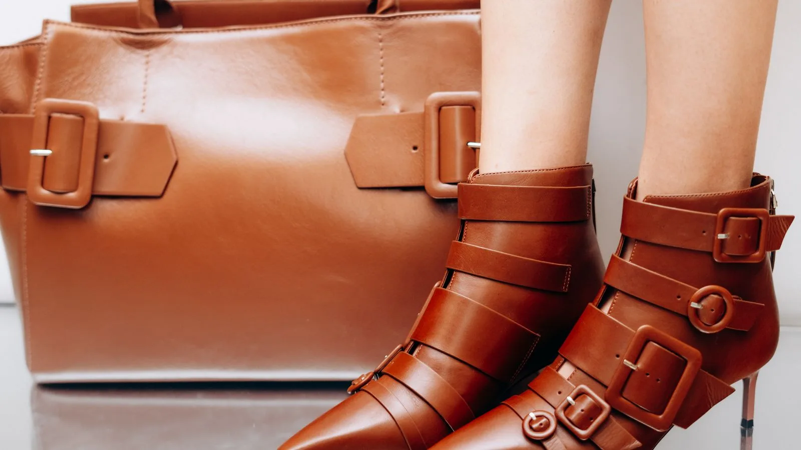 Stylish brown leather boots with matching handbag, perfect for modern fashion enthusiasts.