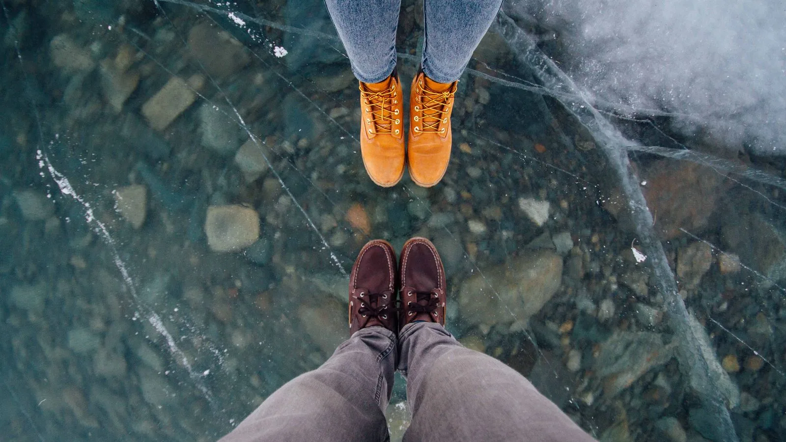 Two people stand on a frozen lake showing their winter boots and jeans in Sachseln, Switzerland.