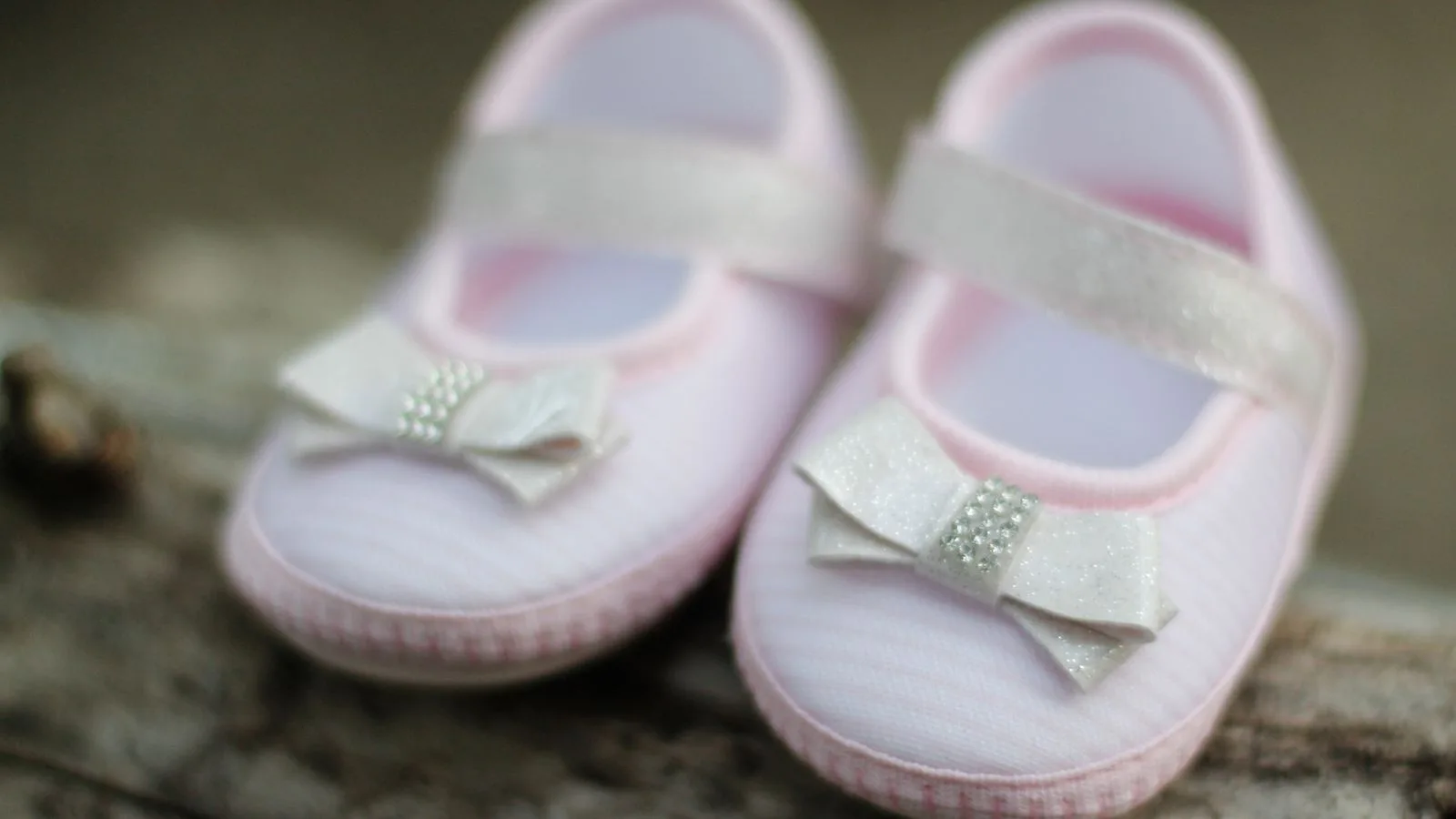 Close-up of adorable pink baby shoes with decorative bows, perfect for expecting parents.