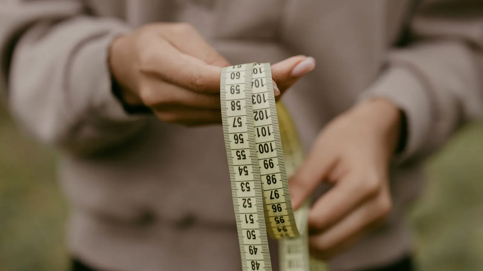 Hands holding a yellow tape measure, perfect for concepts like construction or sewing.